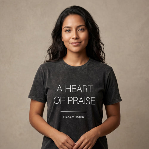 Woman wearing the "a heart of praise psalm 150:6" minimalist graphic tee in a soft neutral studio setting, calm and welcoming.