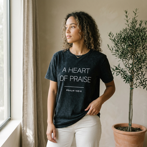 Woman wearing the "a heart of praise psalm 150:6" motivational t shirt in warm natural sunlight with a peaceful, reflective mood.
