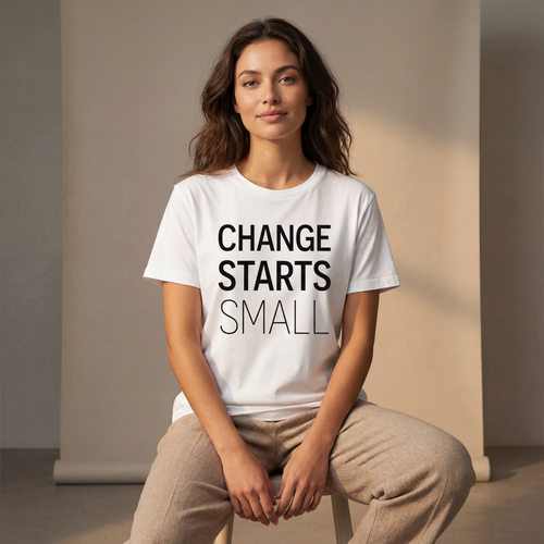 Woman wearing the "change starts small" minimalist graphic tee in a soft neutral studio setting, calm and welcoming.