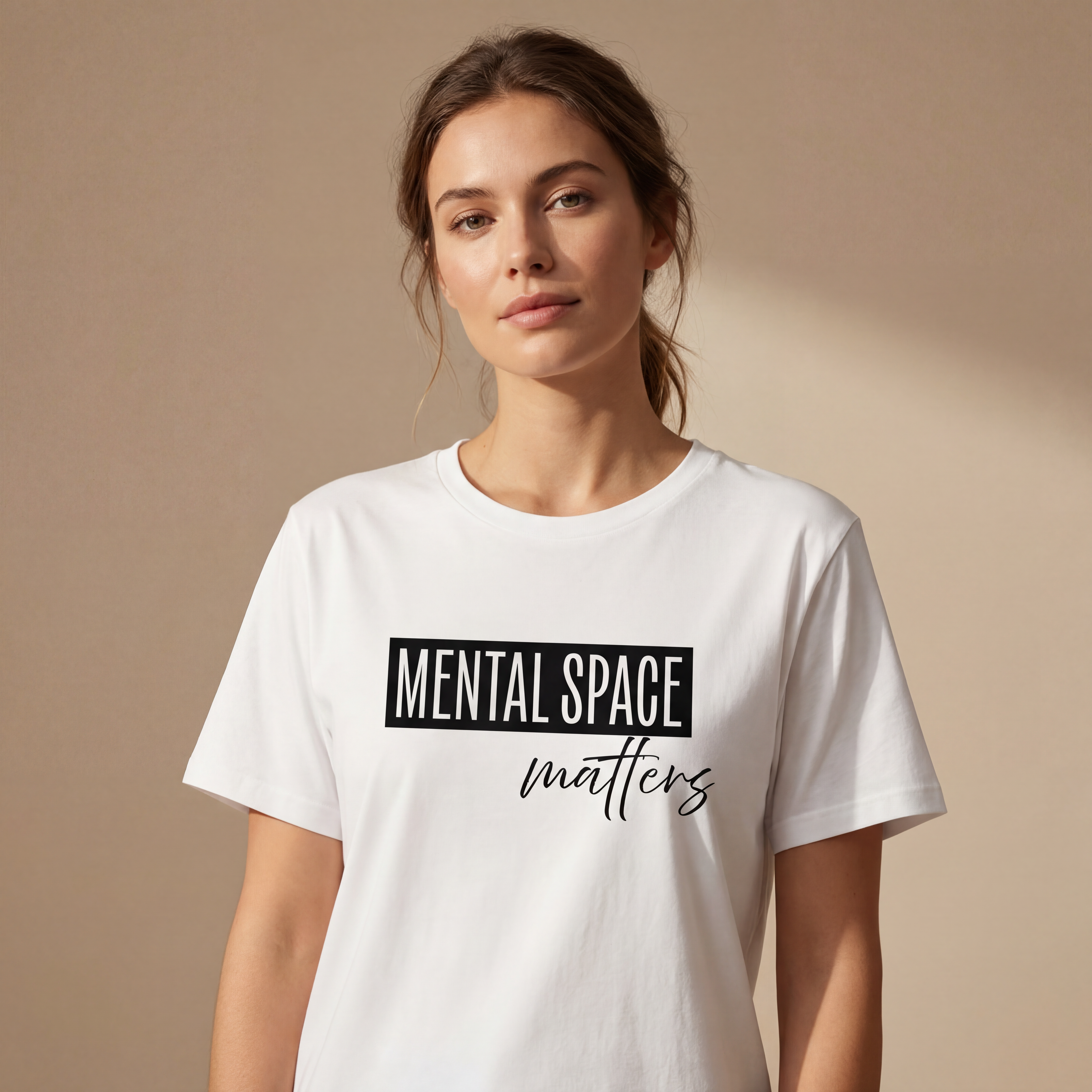 Woman wearing the "mental space matters" minimalist graphic tee in a soft neutral studio setting, calm and welcoming. 2