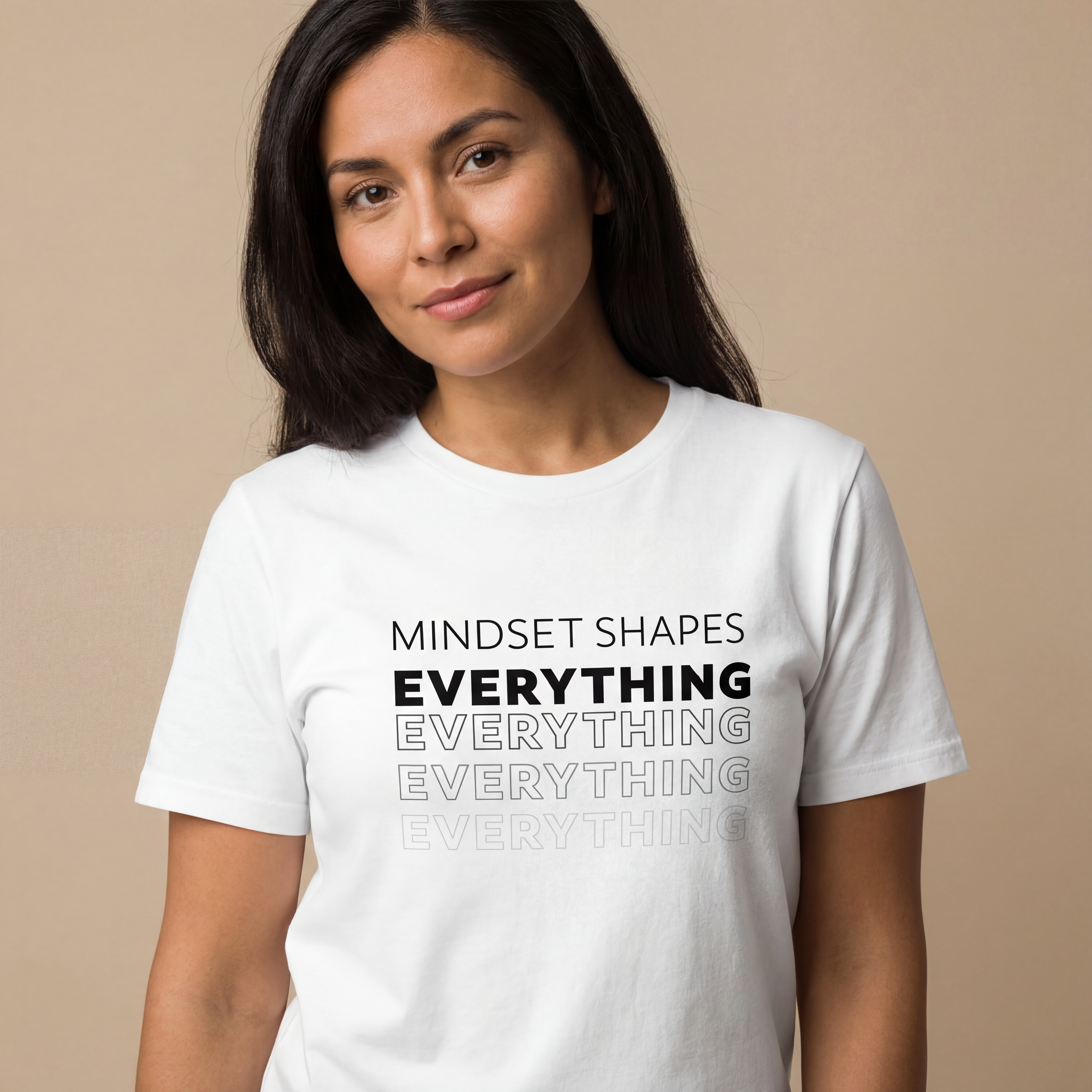 Woman wearing the "mindset shapes everything" minimalist graphic tee in a soft neutral studio setting, calm and welcoming.