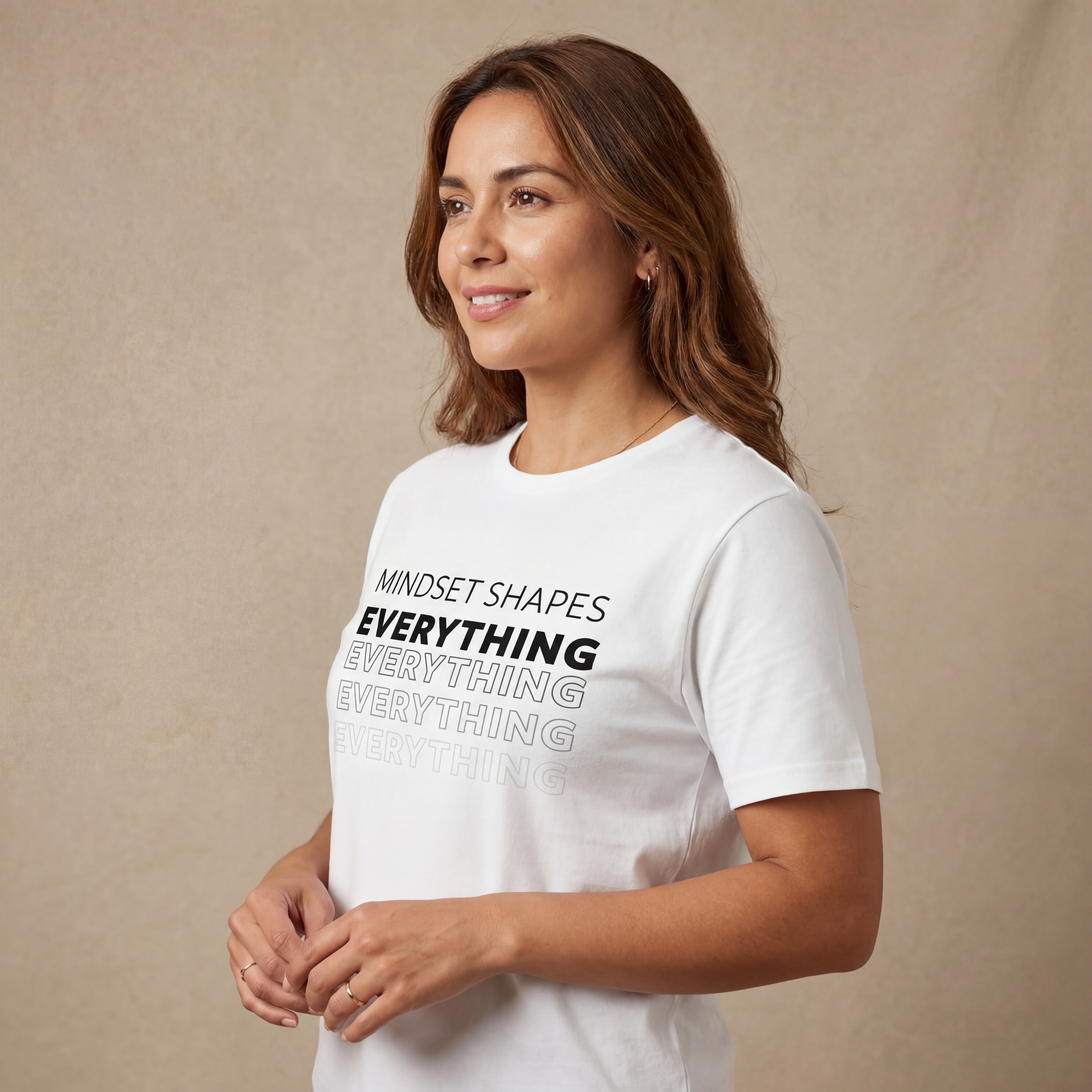 Side angle studio view of a woman wearing the "mindset shapes everything" minimalist graphic tee with a calm, natural expression.